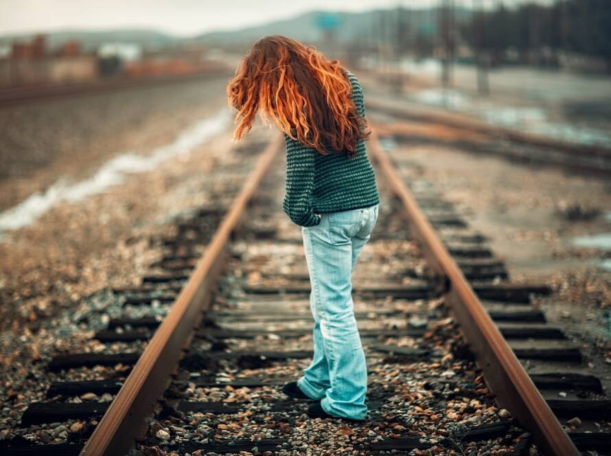 Femme seule marchant sur une voie ferrée, symbolisant une séparation et la décision de divorcer seule.