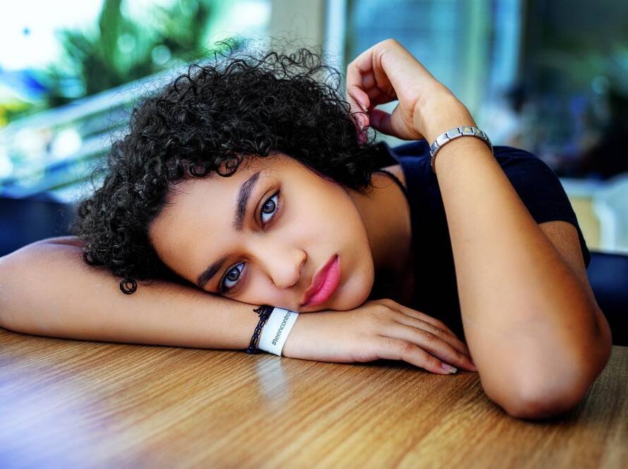Adolescente assise, avachie sur une table, regard dans le vide, symbolisant la difficulté émotionnelle des enfants pendant un divorce.